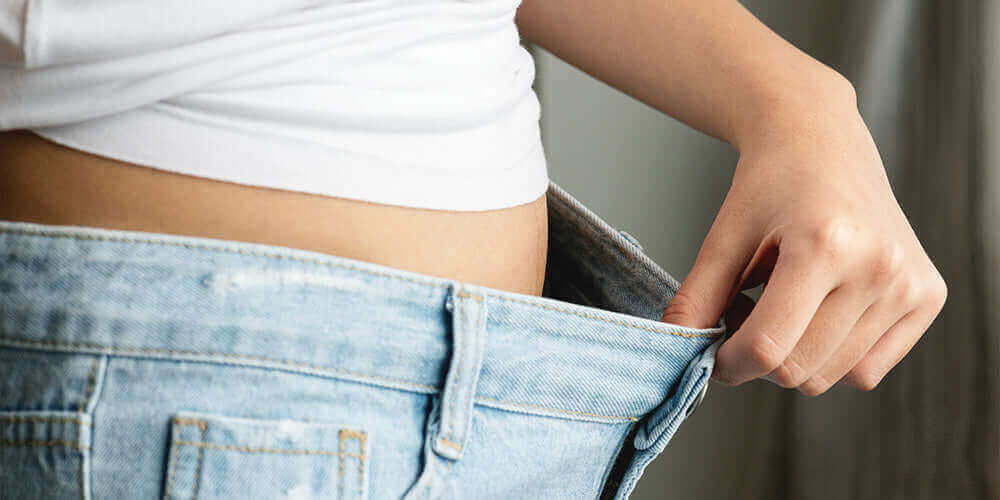 жінка розтягує штани щоб оцінити чи допомогло вживання NMN їй схуднути