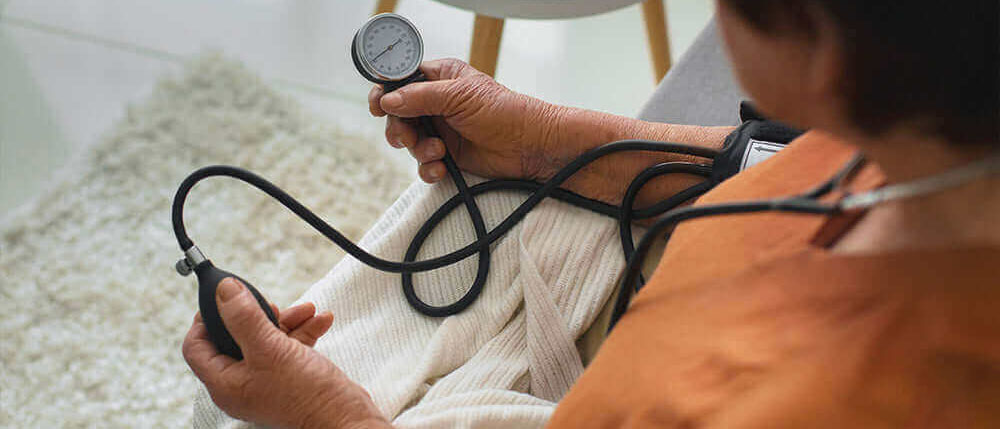 жінка похилого віку вимірює свій артеріальний тиск за допомогою тонометра